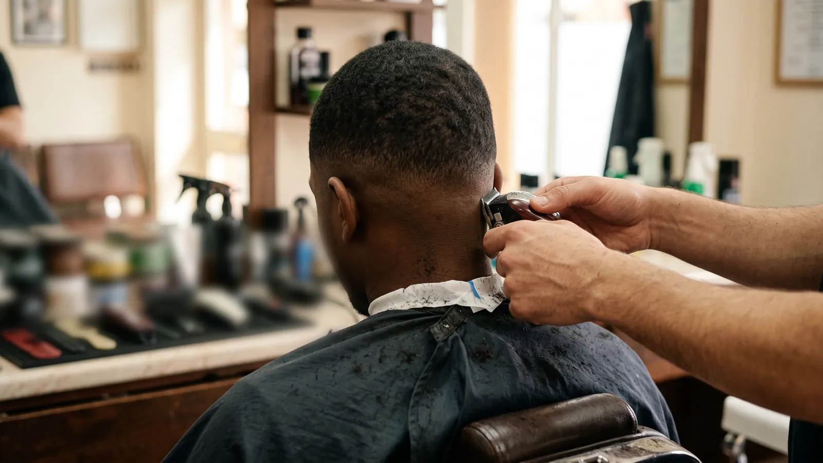 Barber finishing a skin fade in a small barber shop
